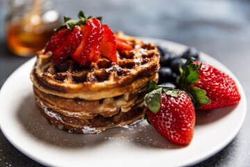 Waffles with strawberries and blueberries served with orange juice