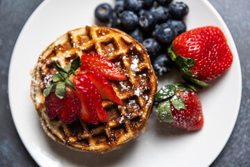 Waffles with strawberries and blueberries served with orange juice