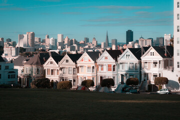 Victorian and Edwardian houses known as the Painted Ladies in Alamo Square, San Francisco, showcasing colorful facades against the backdrop of the city's downtown skyline under a clear blue sky