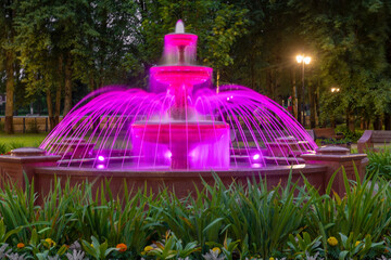 Fountain illuminated with multicolored light on a summer evening in the park