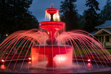 Fountain illuminated with multicolored light on a summer evening in the park