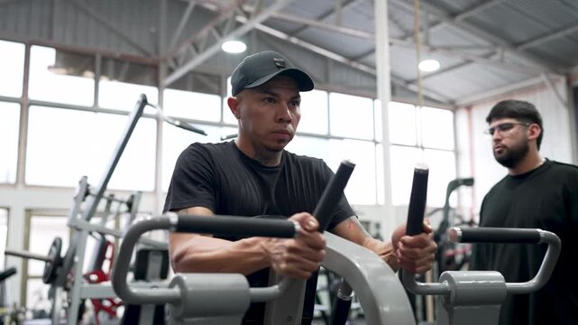 Determined man building muscle strength and endurance while working out on a rowing machine at the gym