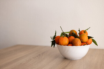 Full bowl of fresh tangerine on a wooden table.