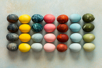 Naklejka premium A beautiful array of hand-dyed Easter eggs in various colors, neatly arranged in rows. This colorful display celebrates the spring season and Easter traditions with creativity