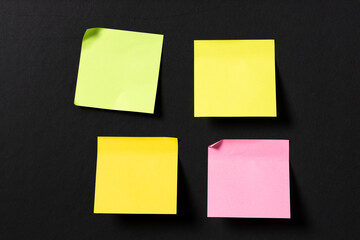 four blank colorful sticky notes on black wall. Template mock up