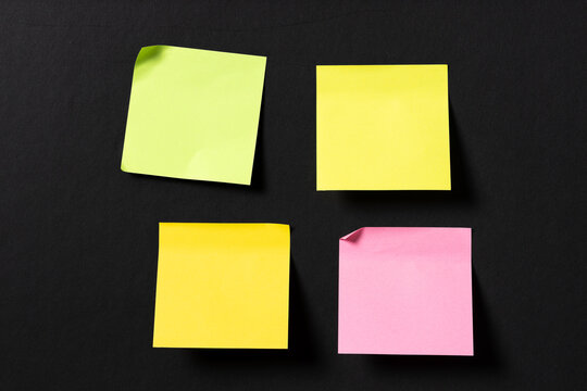 four blank colorful sticky notes on black wall. Template mock up - Powered by Adobe