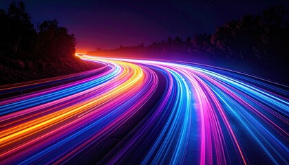 Long exposure shot of car trails glowing with vibrant neon colors on a winding highway at night