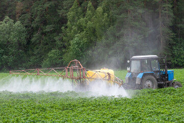 A tractor sprays fresh potatoes with pesticides. This pest control process is essential for growing and protecting plants