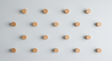 A minimalist geometric pattern of small, round wooden pegs arranged in a staggered grid against a clean, light grey background