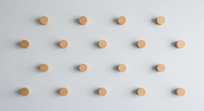 A minimalist geometric pattern of small, round wooden pegs arranged in a staggered grid against a clean, light grey background