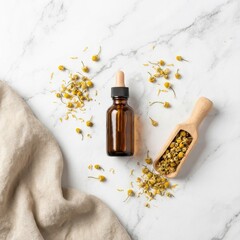 Chamomile essential oil bottle with dried flowers on marble