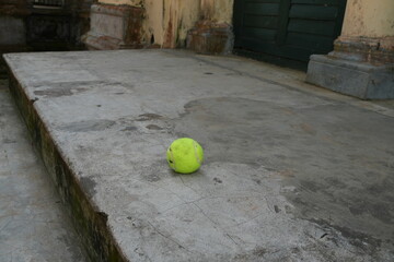 A vibrant green ball resting on weathered concrete steps