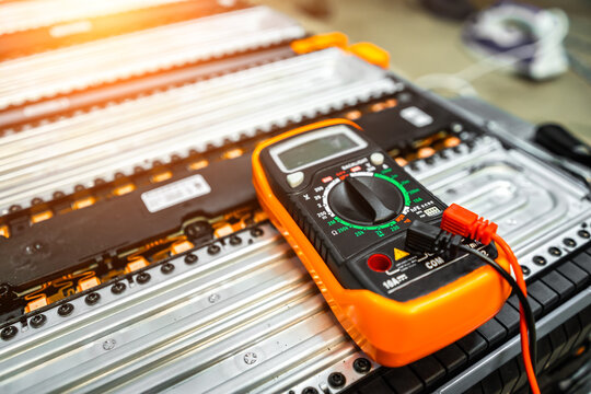 the multimeter is lying on the battery of an electric car on a blurry background.