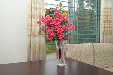 Vase of Pink Flowers on a Wooden Table by a Window