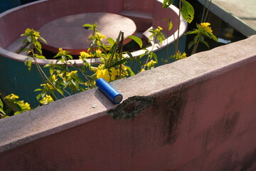 Blue 18650 Battery Resting on a Weathered Concrete Wall