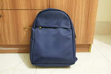 Navy Blue Minimalist Backpack Against Wooden Cabinet