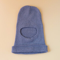 Gray knitted winter wool hat on color background.
