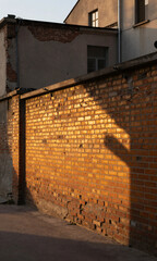 warm brick wall worn mortar situated foreground empty alleyway casts deep shadows crumbling city