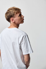 Young man in a white t shirt seen from behind with a subtle side glance, casual fashion, minimal...