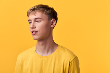Fototapeta premium Man, young, casual, yellow, background, studio, clothing, tshirt on model in a warm yellow setting for fashion, lifestyle and minimalist vibe