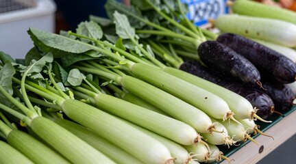 Obraz premium Close-up of fresh produce at a farmer's market showing taro stems, gai lan and zucchini