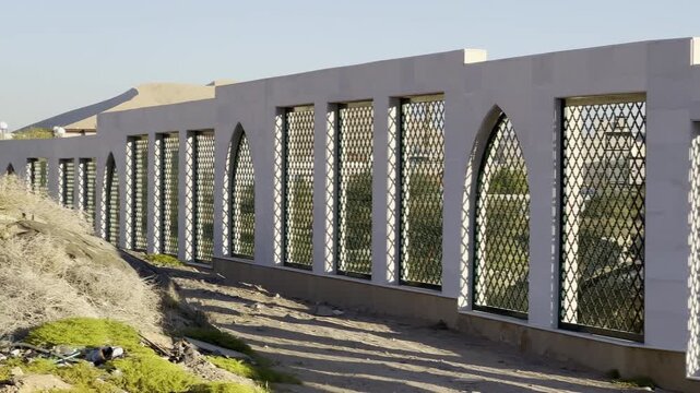 The sacred burial ground of the martyrs (Shuhada) of the first Islamic Battle of Badr, viewed through a traditional Islamic fence, with a close-up on the marble monument.