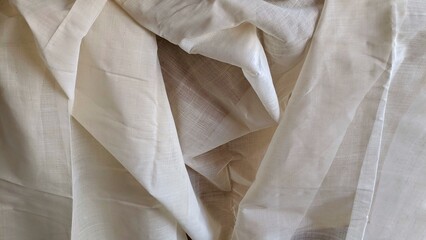 Close-up view of soft white cotton fabric with natural folds and wrinkles. Minimal textile background for fashion, interior design and material concepts.