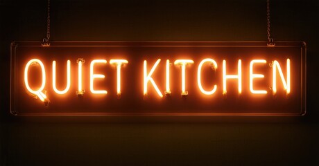 Bright neon sign displays Quiet Kitchen. Rectangular shape hangs via metal chains against dark background. Warm orange glow dominates image.
