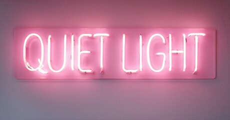 Pink neon sign displays words Quiet Light against pale wall. Minimalist aesthetic, soft glow, modern design element.
