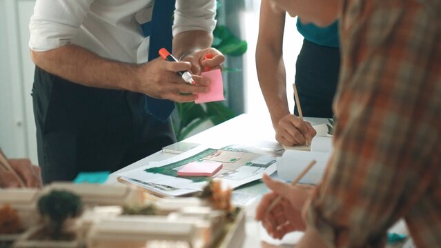 Close up of smart business team hand working together to plan design while looking at project plan from tablet and discussing about blueprint and building construction at meeting table. Alimentation.