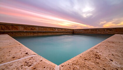 Obraz premium Tranquil Poolside Scene Under a Colorful Sunset Sky.
