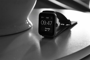 Stylish modern smartwatch displayed on a reflective surface, showing time and health icons, representing wearable technology, fitness tracking, and digital lifestyle.