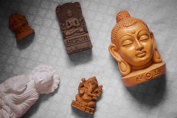 An artistic flat lay of Indian spiritual statues including Buddha and Ganesha placed on a decorative background, symbolizing meditation, peace, spirituality, and cultural heritage