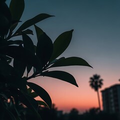 Close-up silhouette of green leaves against a soft pink and blue sunset sky with a palm tree in the distance