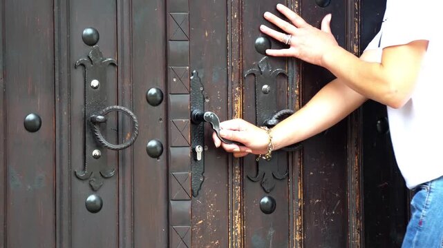 Woman opening an antique wooden door and steel door handle