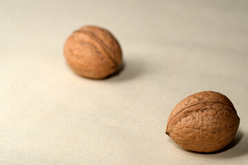 Two walnuts resting on a soft, textured surface in natural light