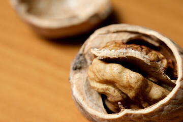 Cracked walnut revealing its rich, golden interior on a wooden surface