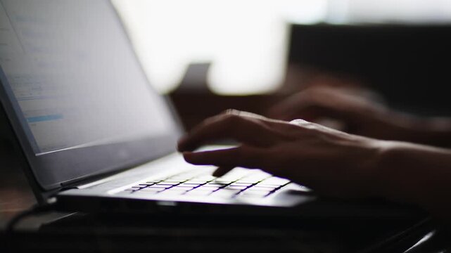 Hands of a developer working on laptop in the dark, typing code, developing early in morning
