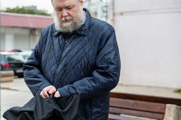 Man adjusting umbrella on bench in city residential area, everyday urban life in rainy weather