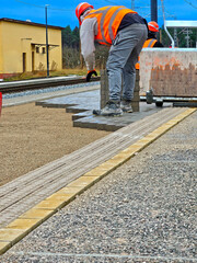 Worker laying paving slabs on the platform of a railway station