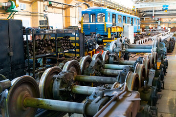 A blue train is positioned inside a large maintenance facility. Tools and materials are organized around the workshop, highlighting the industrial atmosphere of train repairs