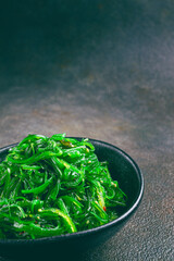 Chuka salad, made from fresh seaweed, with sesame dressing, served in a black bowl,