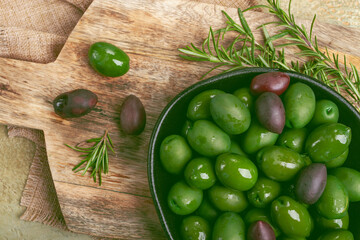 Chalkidiki olives, classic Greek green olives, in a bowl on a cutting board, top view, without people,