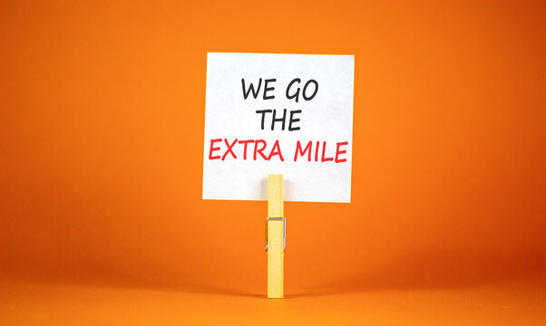 Support, help we go the extra mile symbol. Concept words We go the extra mile on beautiful white paper on clothespin. Beautiful orange background. Business we go the extra mile concept. Copy space.