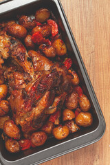 Pork knuckle, baked with vegetables, new potatoes , on a baking sheet, homemade, no people,