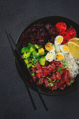 Fresh poke bowl with tuna, avocado, and vegetables served on a black plate