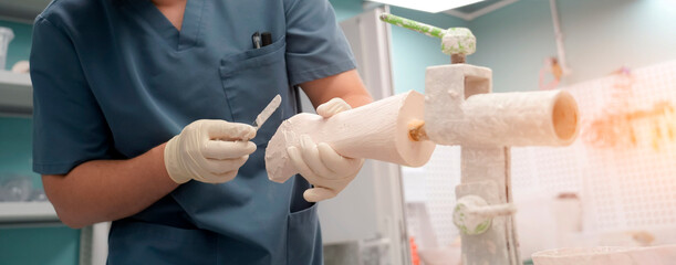 A skilled technician carefully shapes a prosthetic limb using a carving tool in a well-lit clinic. The focus is on creating a perfect fit for the patient, showcasing attention to detail