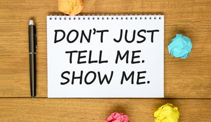 Naklejka premium Tell or show symbol. Concept words Do not just tell me, show me on beautiful white note. Beautiful wooden background. Black pen. Business tell or show concept. Copy space.