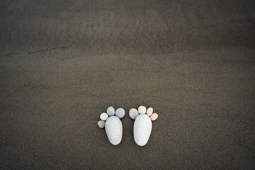 Stones and rocks on sand carefully placed to represent footprint representing zen art in zen garden style. Symbolic image of peace, meditation, calm and mental health. 