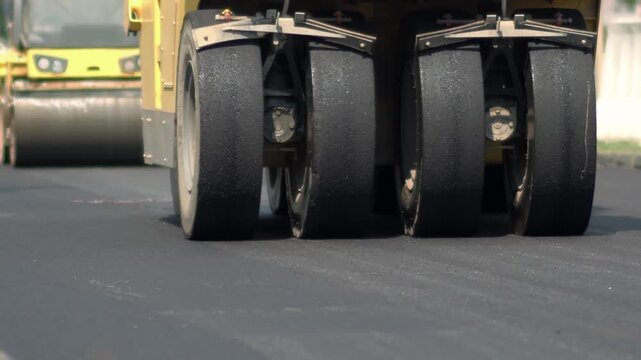 Steam roller machines on laying of new asphalt road pavement on a construction site, highway construction, workers and road construction machinery scene